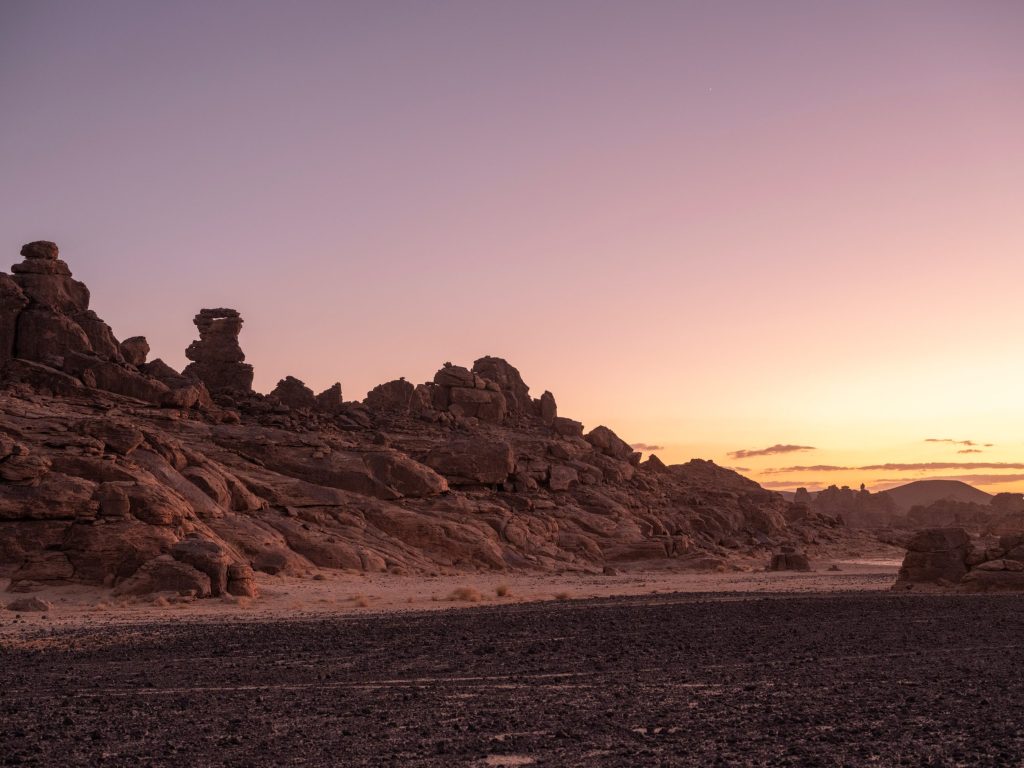 Ancient stone structures scattered across the volcanic fields of the Harrats at sunset.